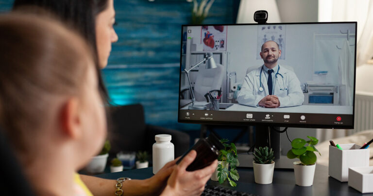 Adult and child looking at a computer screen with a Doctor on it